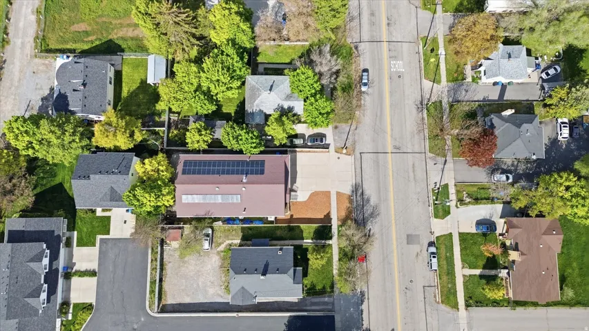 Property featuring solar panels on the roof, a paved driveway, and mature landscaping