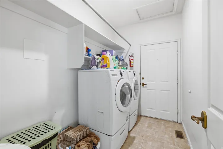 Dedicated utility area featuring tile flooring, white shaker-style wall cabinetry, and a paneled entry door