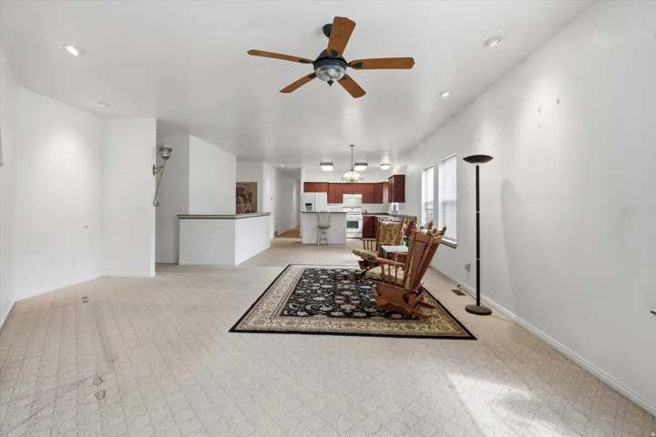 Open-concept living area with neutral carpeting and recessed lighting
