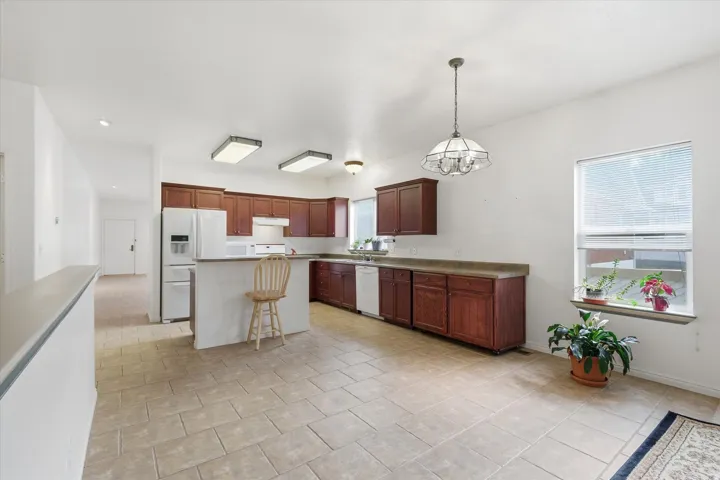 Spacious kitchen featuring warm wood cabinetry, light-toned countertops, and tile flooring