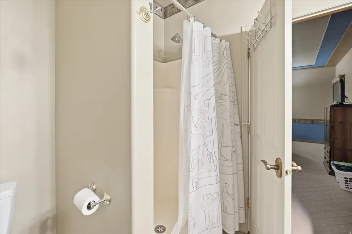 Enclosed shower stall with a neutral-toned surround and an overhead shower head