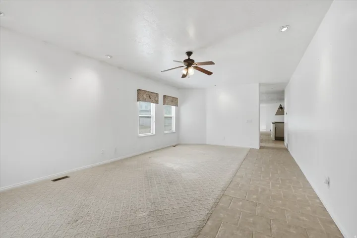 Spacious interior featuring a neutral color palette, recessed lighting, and a ceiling fan