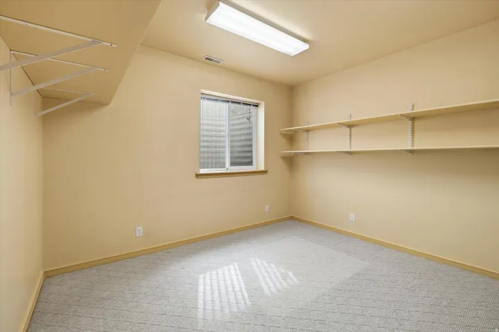 Room featuring neutral-toned walls, patterned carpet flooring, and a single window with blinds