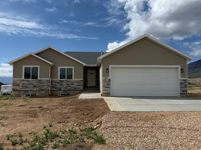 Contemporary ranch-style exterior featuring a neutral stucco facade and a stone veneer accent