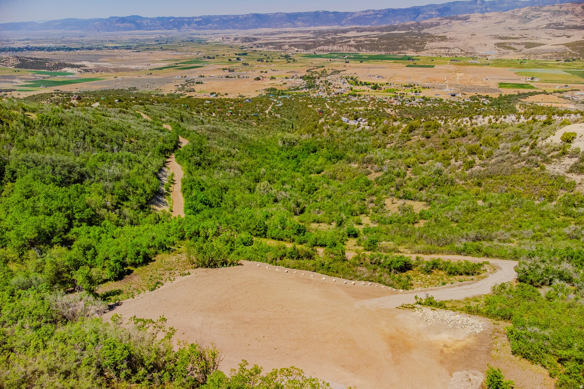 Elevated property featuring natural terrain, mature green foliage, and expansive open land