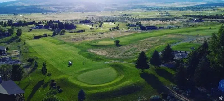 Expansive green spaces featuring a golf course, surrounding residential properties, mature trees, and distant mountainous terrain