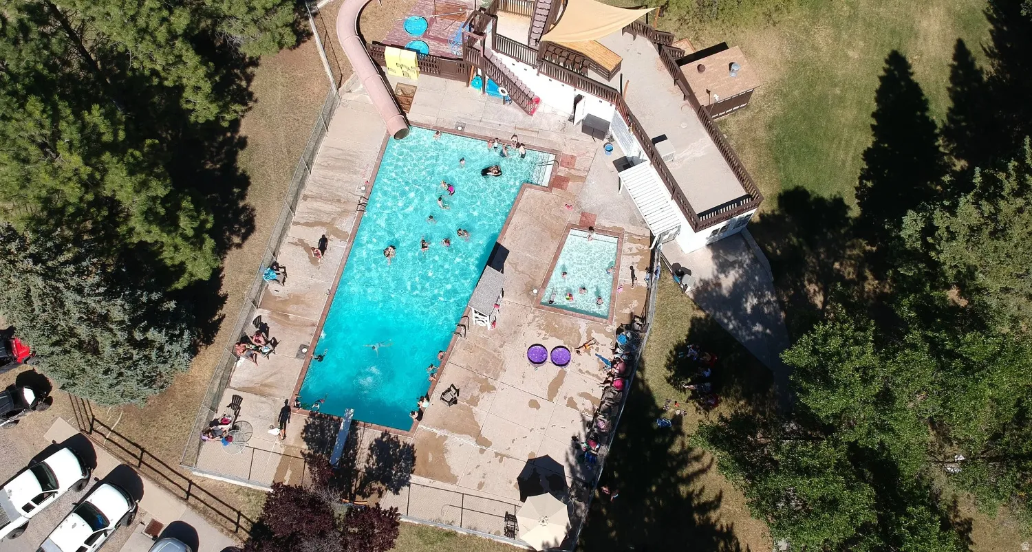 Expansive outdoor pool area featuring a rectangular main pool, a smaller secondary pool, and surrounding concrete decking