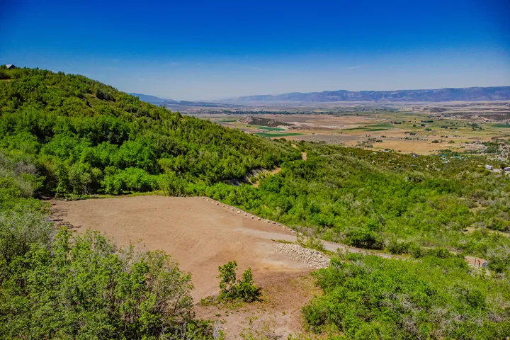 Expansive cleared building site with surrounding mature trees and a vast natural landscape