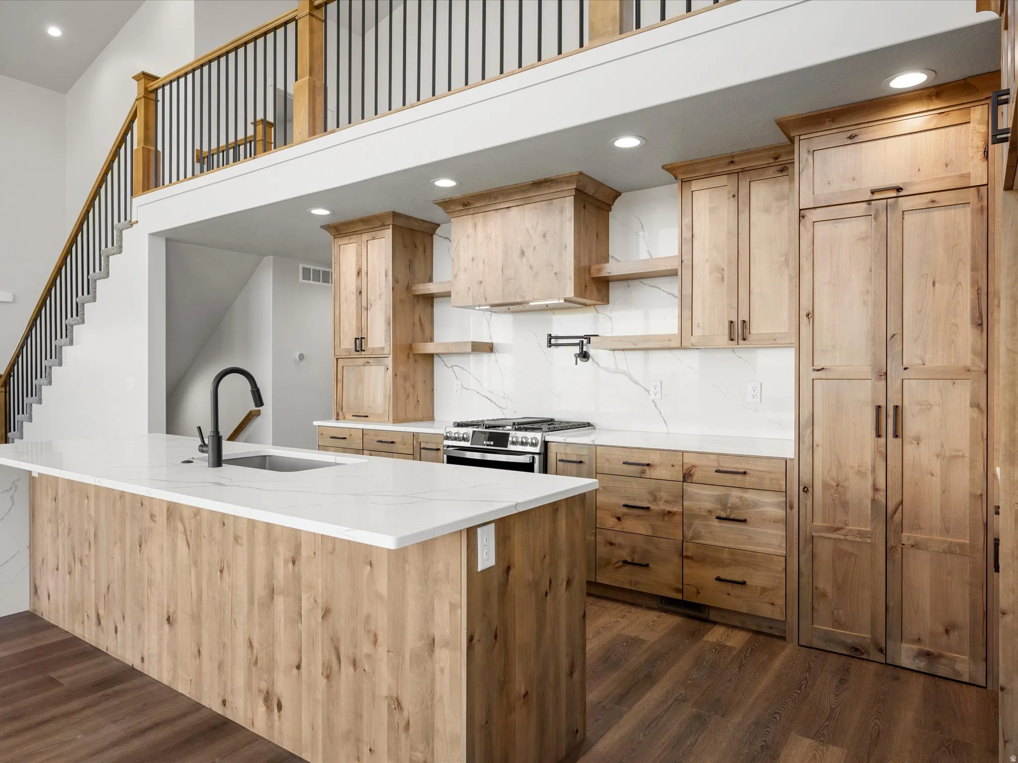Modern kitchen featuring light wood cabinetry, white countertops, and a full backsplash