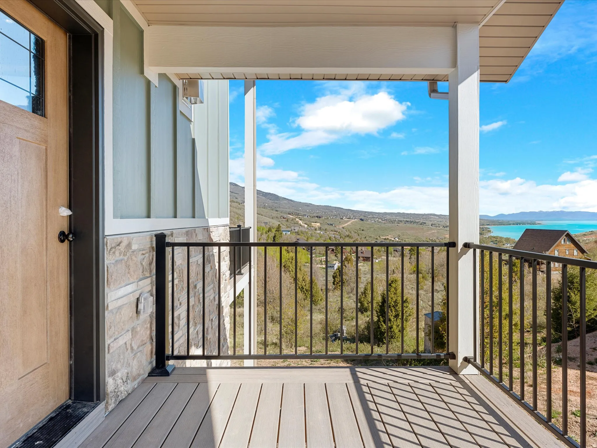 Covered porch featuring wood-look decking and black metal railings