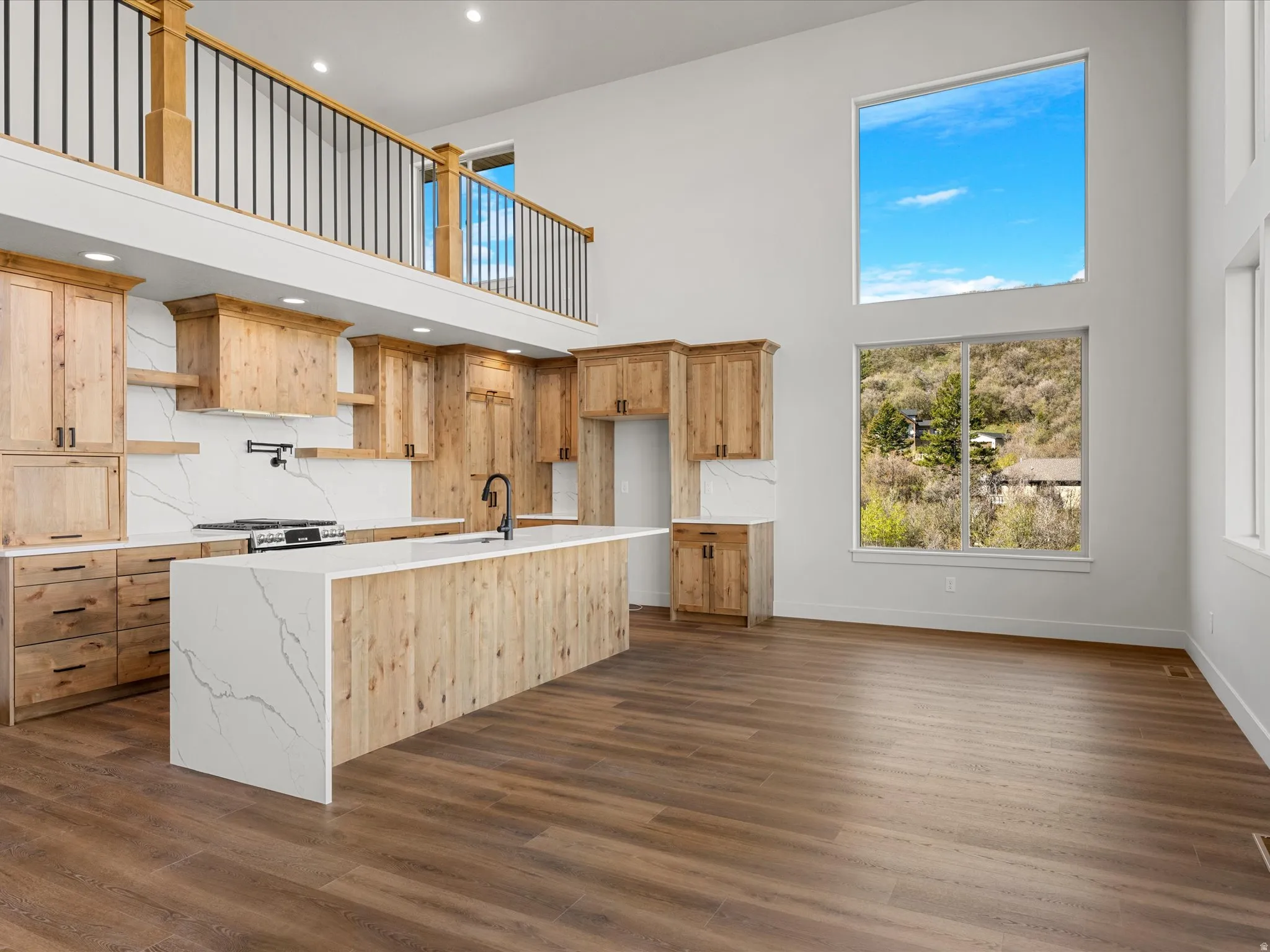 Open-concept kitchen and living area featuring a two-story ceiling and wood-finish flooring