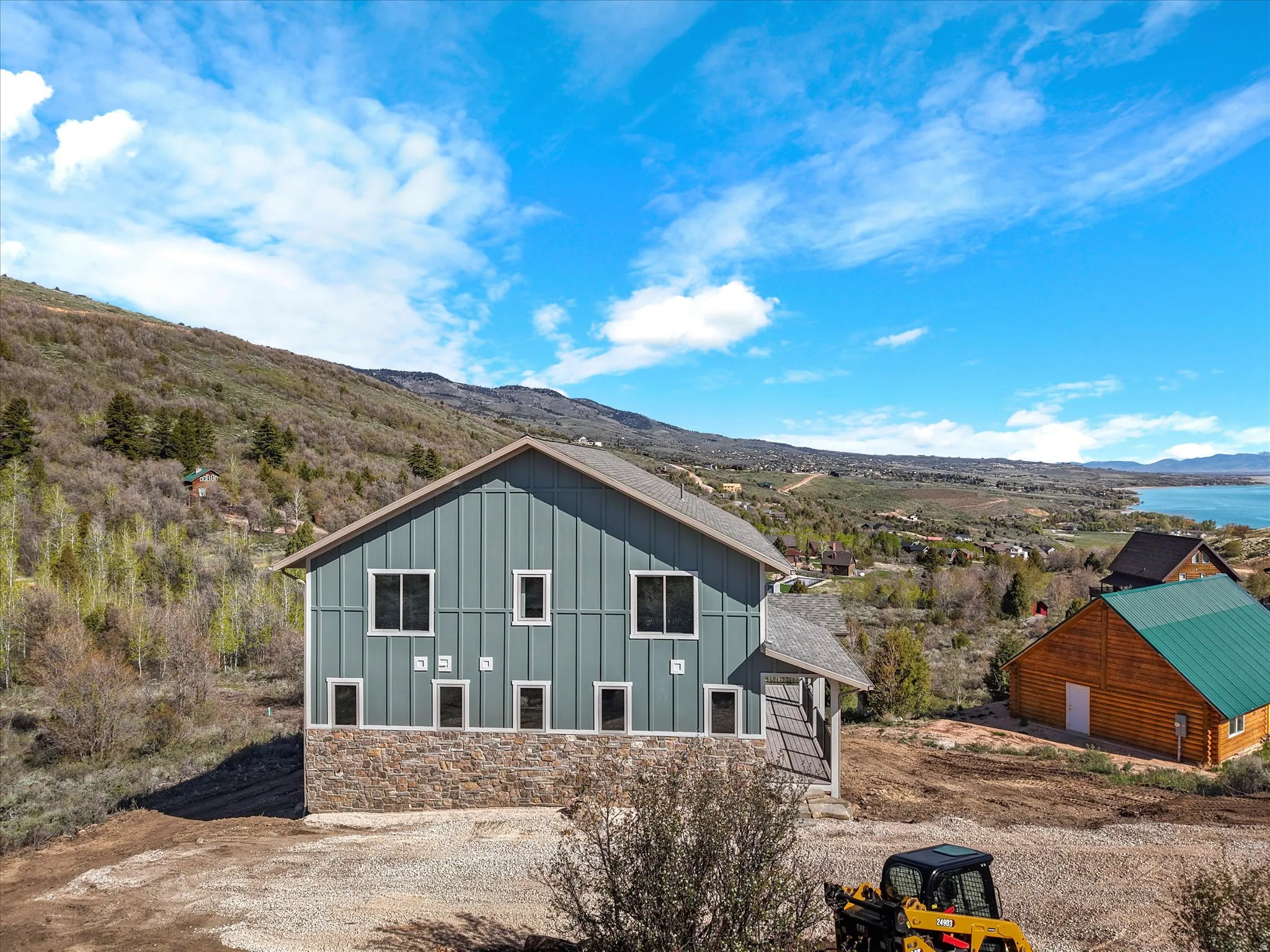 Contemporary home featuring board and batten siding, a stone facade, and multiple window placements