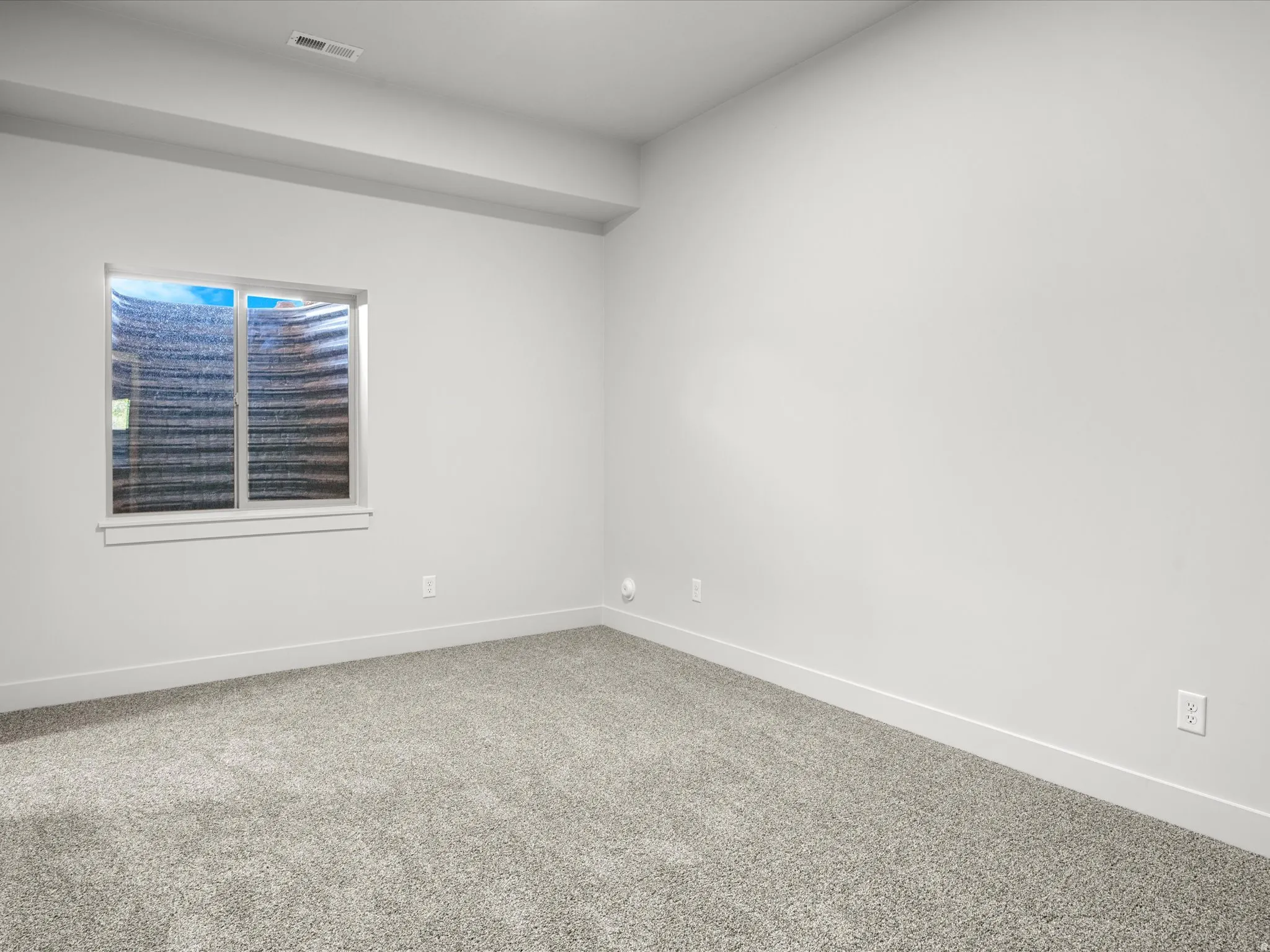 Carpeted room featuring a single window with white trim, light gray walls, and white baseboards