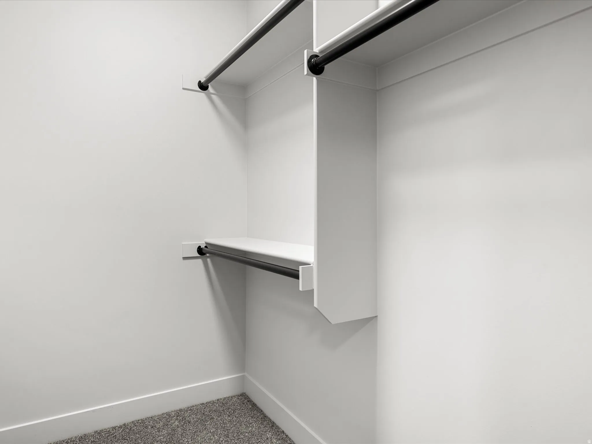 Walk-in closet with white shelving and black metal hanging rods