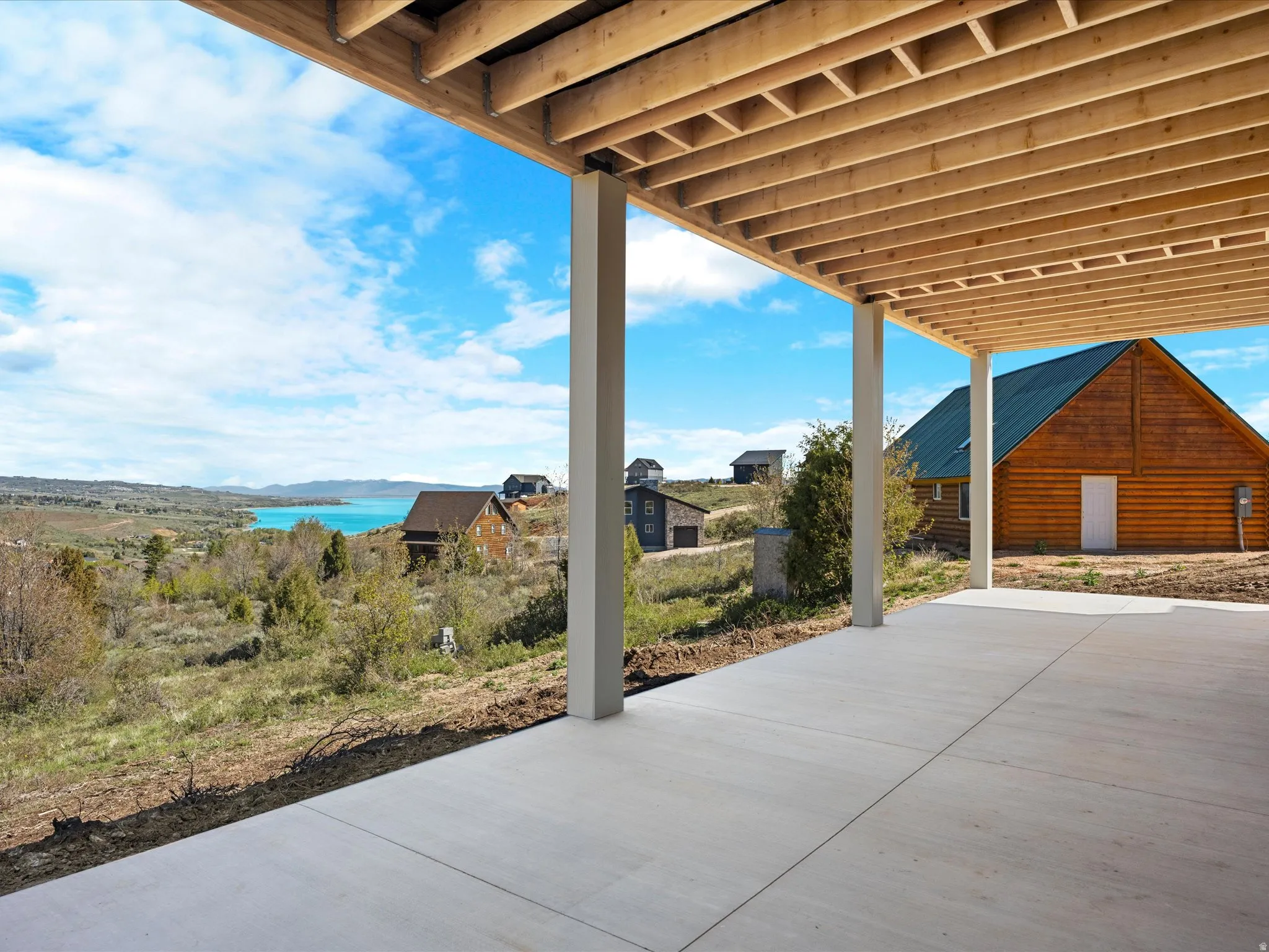 Covered patio with a concrete slab, exposed wood joists, and structural support posts