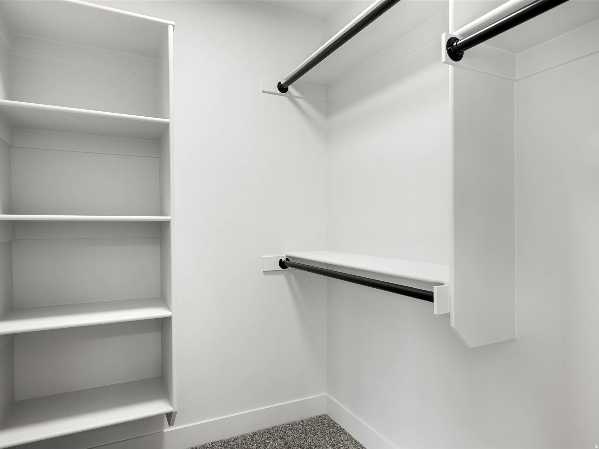 Walk-in closet featuring built-in shelving, white walls, and dark-finish hanging rods