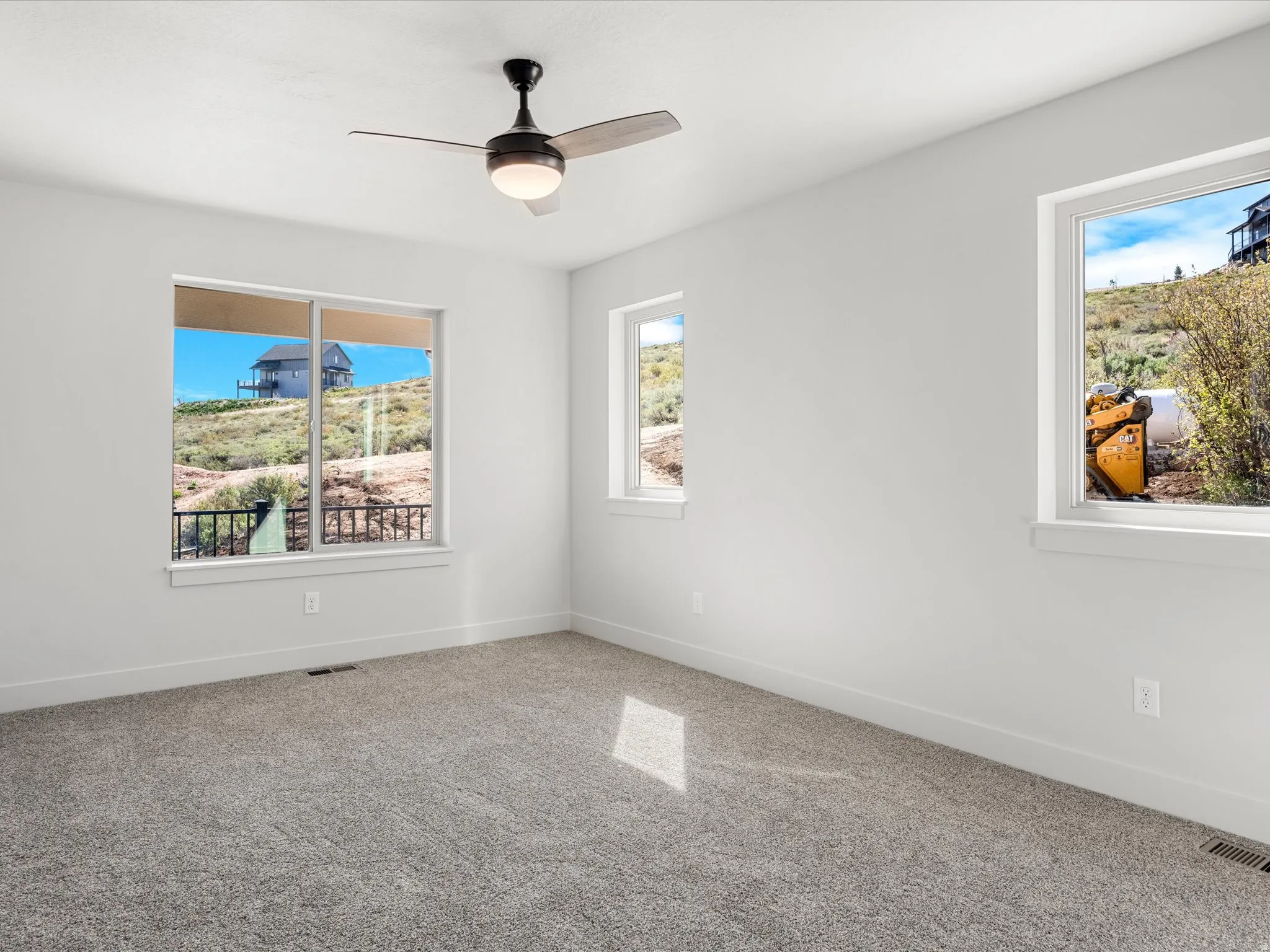 Room with neutral gray carpeting, white walls, and a contemporary ceiling fan with integrated lighting