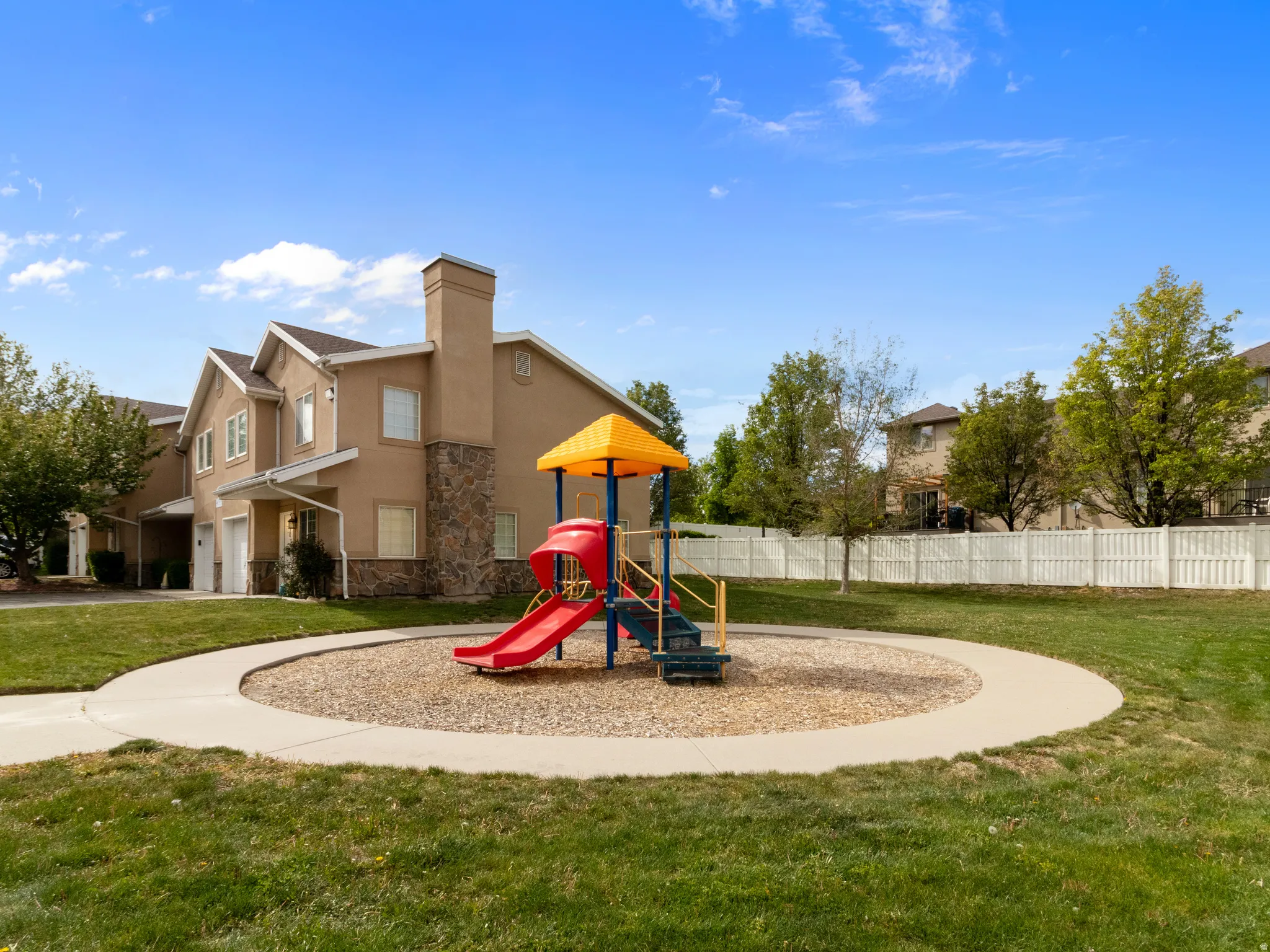 Expansive green space featuring a playground with slides, a manicured lawn, and a circular concrete pathway
