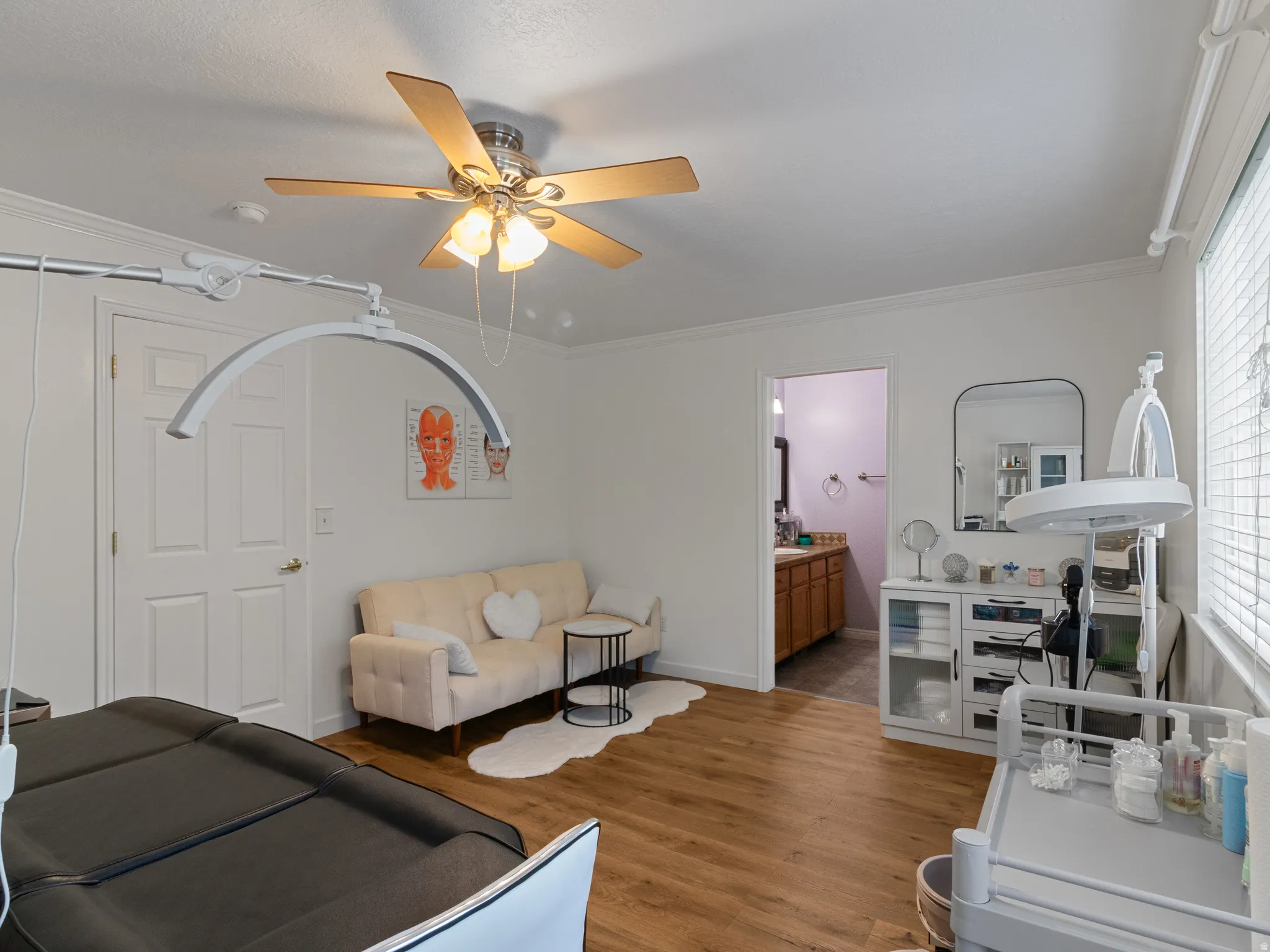 Room featuring wood-finish flooring, a ceiling fan with integrated lighting, white walls, and a window with blinds