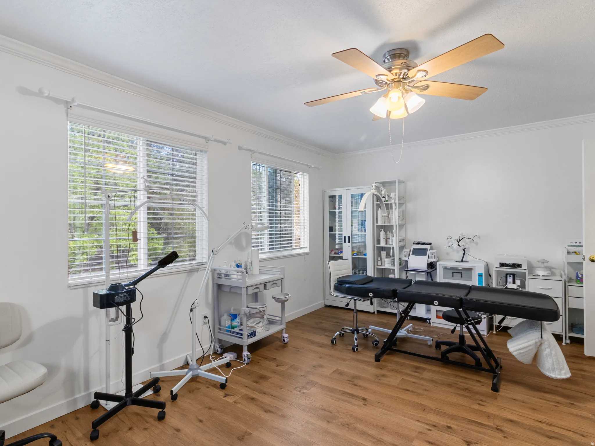 Bright room featuring wood-finish flooring and multiple windows with blinds