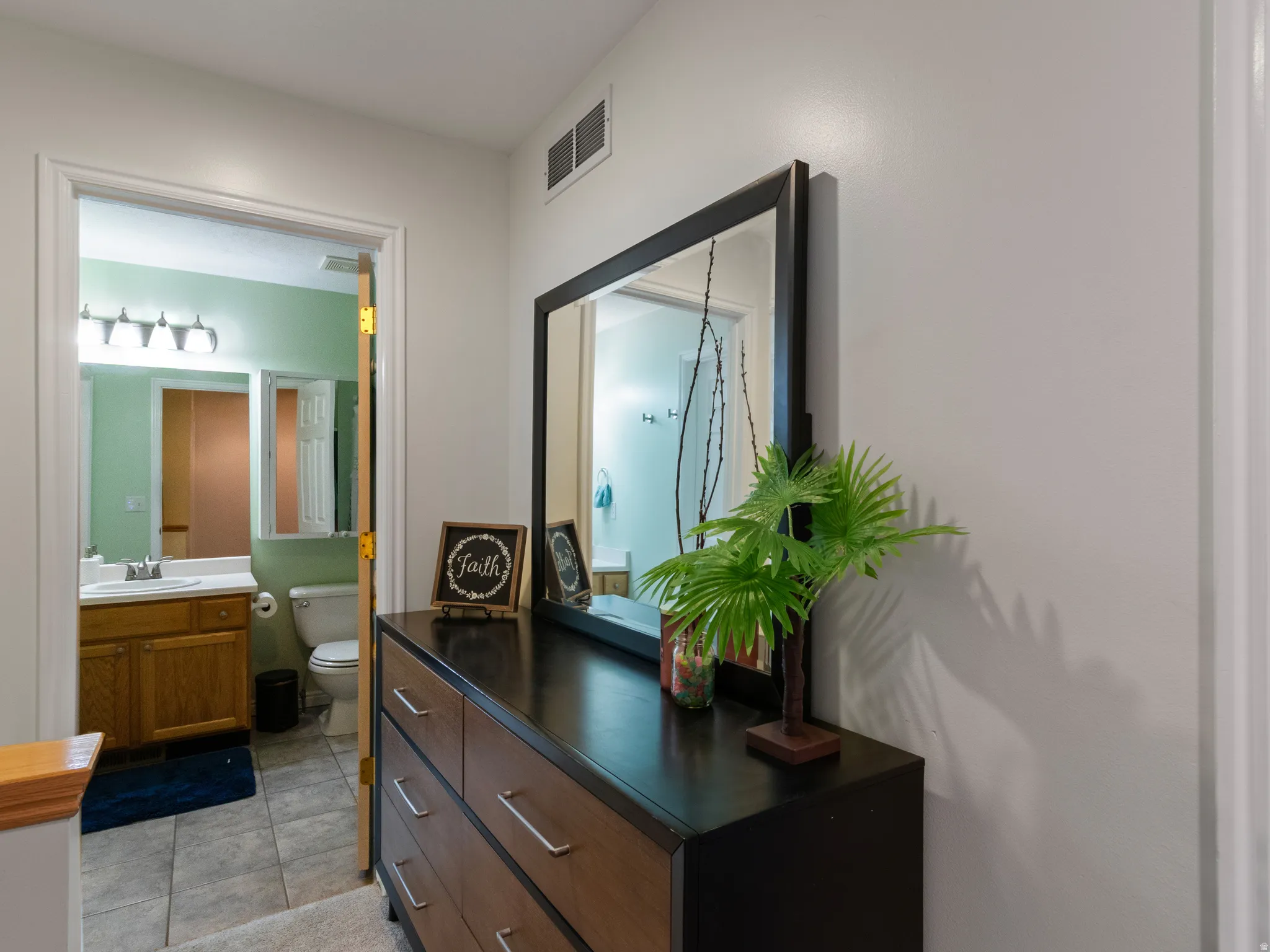 Bathroom featuring a light wood-finish vanity with a white countertop and a four-light fixture