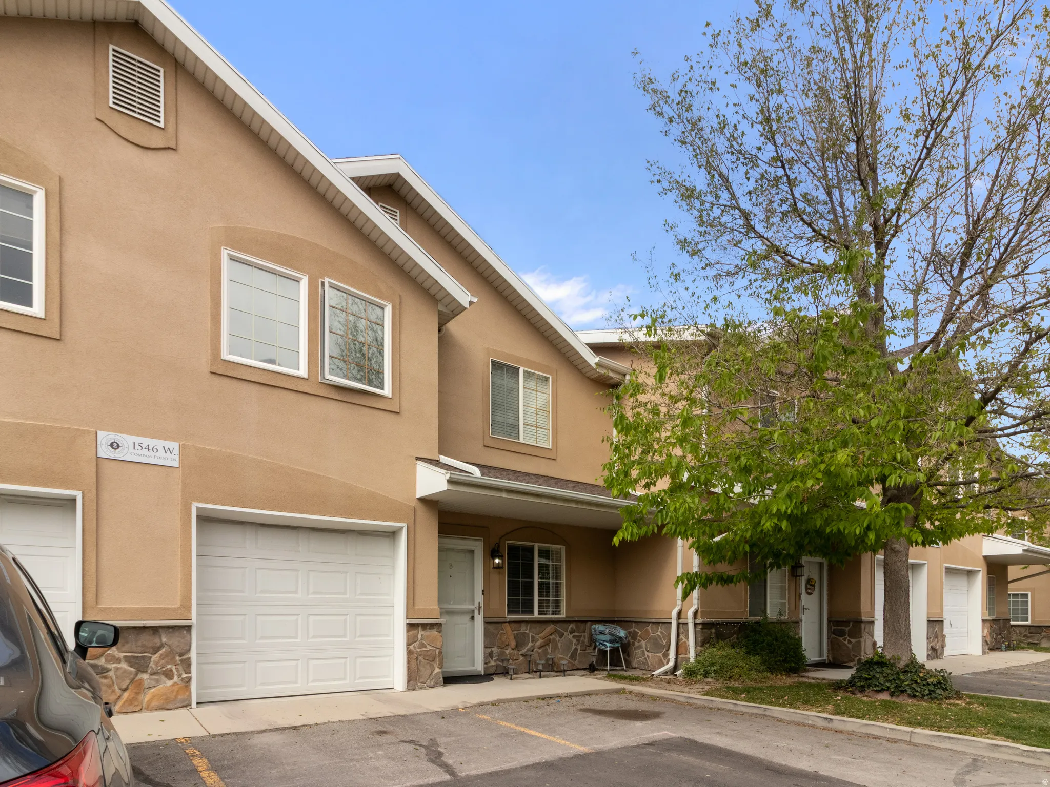Stucco exterior featuring stone accents, white garage doors, and a front entry