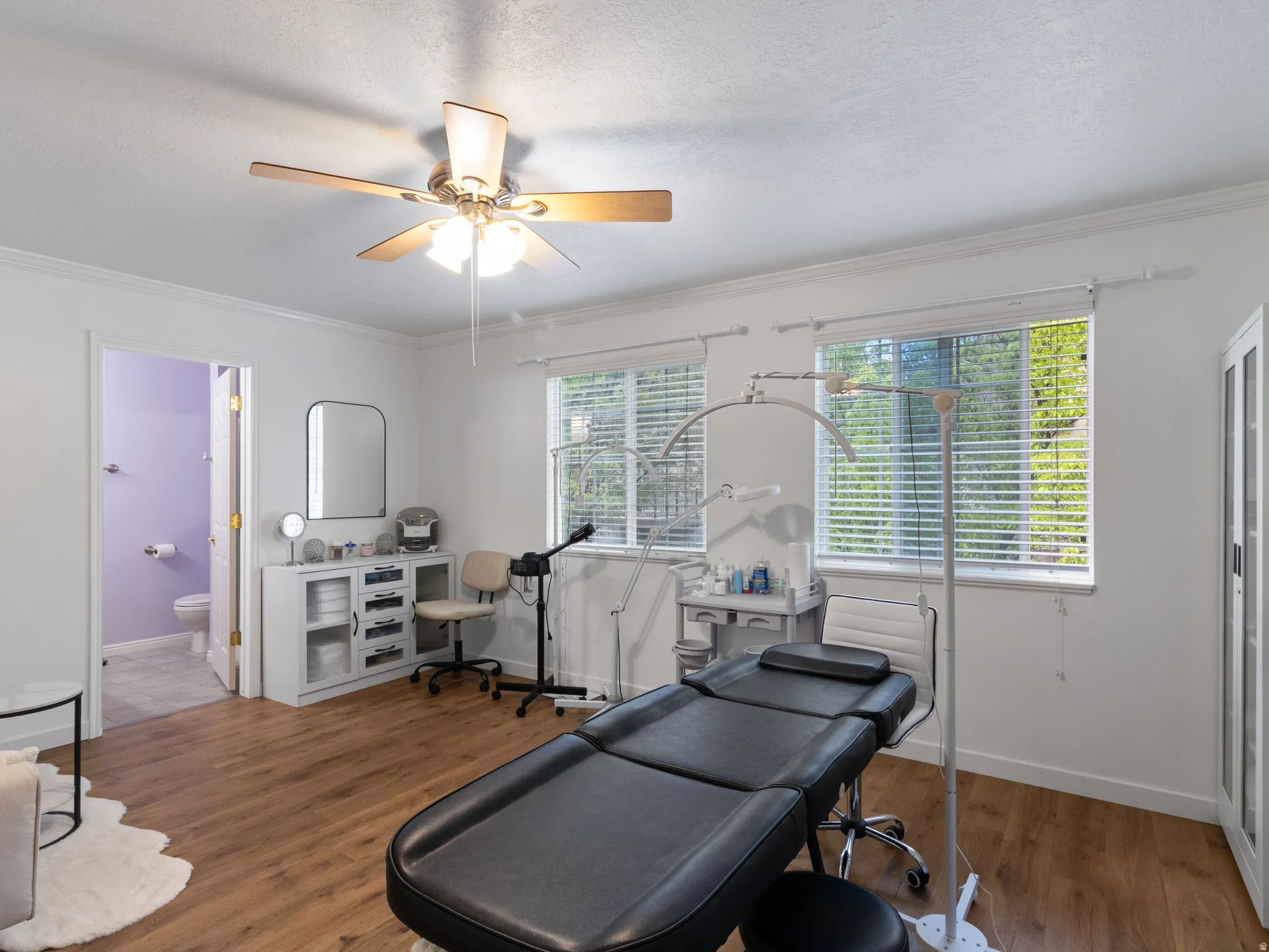 Spacious room featuring wood-finish flooring, white walls, and a ceiling fan with integrated lighting