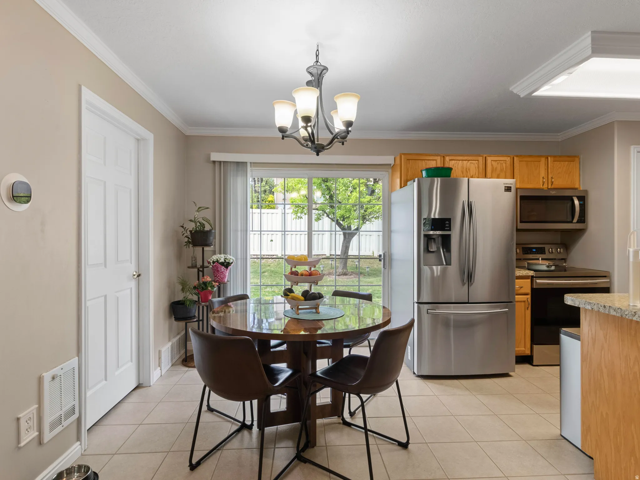Kitchen and dining area featuring tile flooring, stainless steel appliances, wood cabinetry, and a sliding glass door providing exterior access