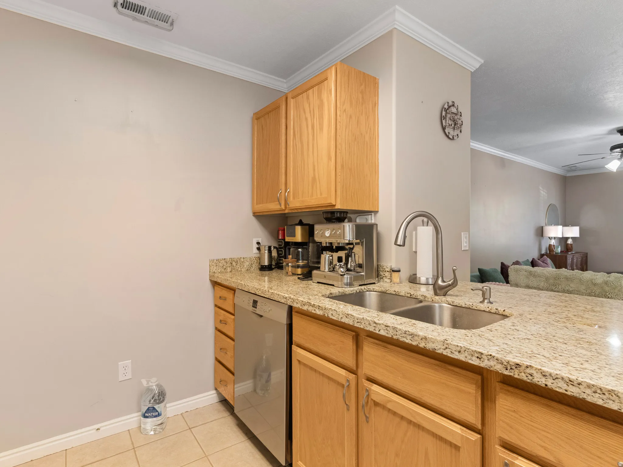 Kitchen area featuring light wood-finish cabinetry, speckled countertops, a stainless steel double basin sink with a high-arch faucet, and a stainless steel dishwasher