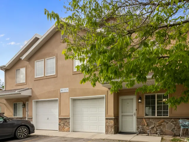 Stucco exterior featuring stacked stone accents, two single-car garages, and white-framed windows