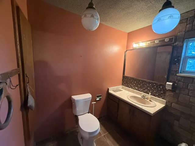 Bathroom vanity featuring an integrated sink, mosaic tile backsplash, and a large mirror