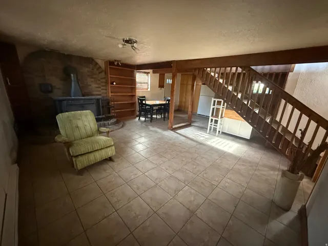 Spacious room featuring tile flooring, a prominent brick fireplace with a wood-burning stove, and extensive built-in wooden shelving