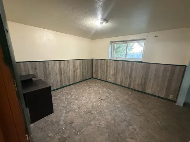 Room featuring light-toned walls, wood-finish wainscoting, and a window providing natural illumination