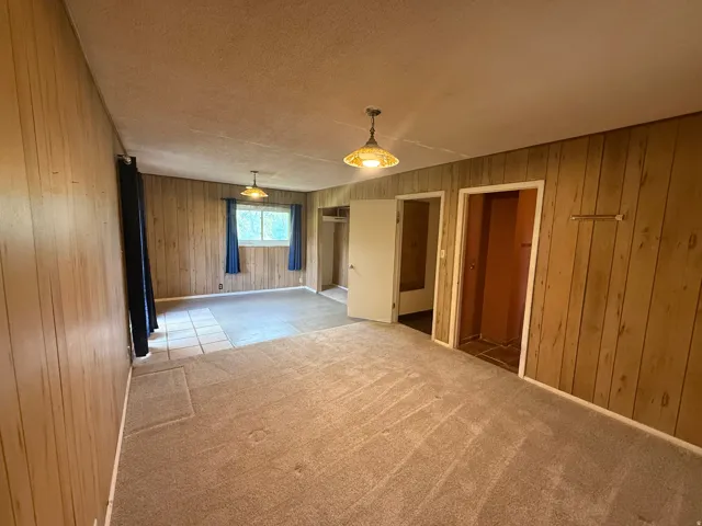 Spacious room featuring wood paneling, a combination of carpet and tile flooring, and two interior doorways