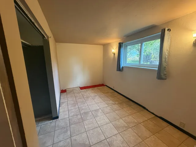 Tiled flooring with a window offering exterior views, complemented by two wall-mounted light fixtures and a bi-fold closet door
