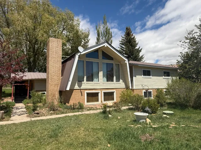 Architectural split-level residence featuring a prominent brick chimney and a distinctive A-frame window section with vertical siding
