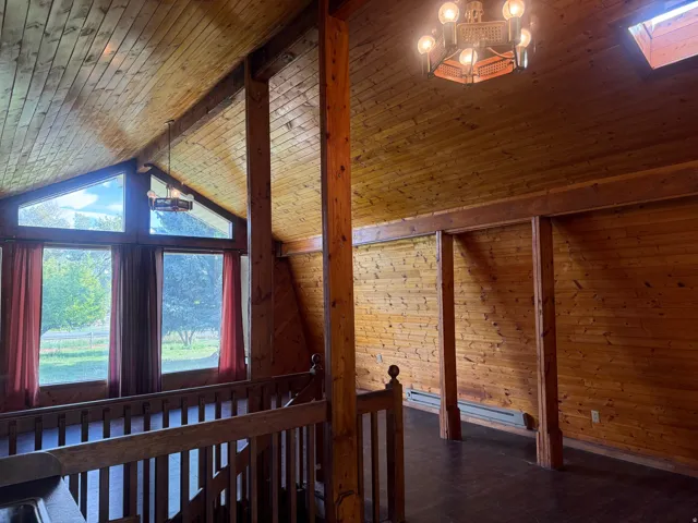 Vaulted ceiling featuring wood-finish paneling and exposed beams