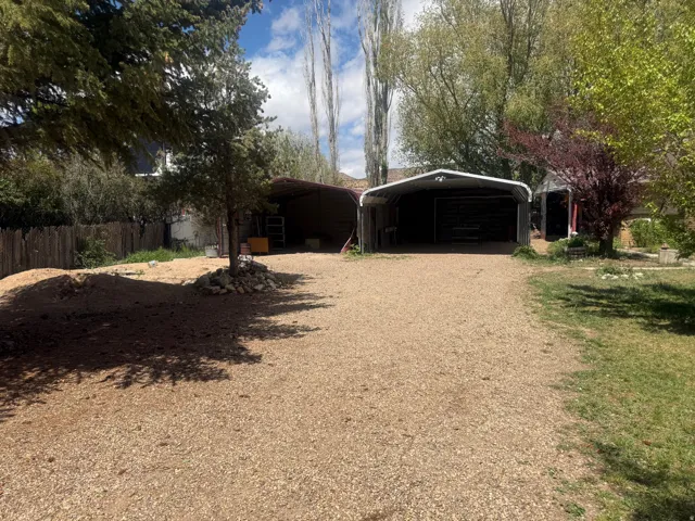 Expansive gravel driveway leading to two covered carports