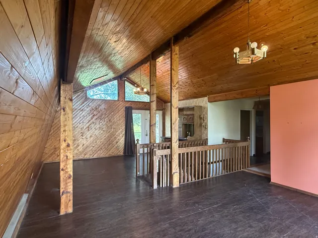 Spacious room featuring vaulted wood-paneled ceilings, complementary wood-paneled walls, and wood-finish flooring