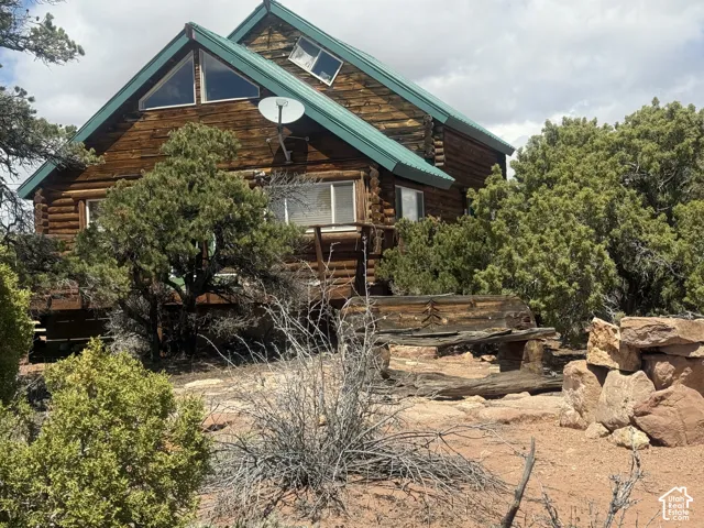 Log-style exterior featuring a green metal roof, triangular windows, and a raised wood-finish deck