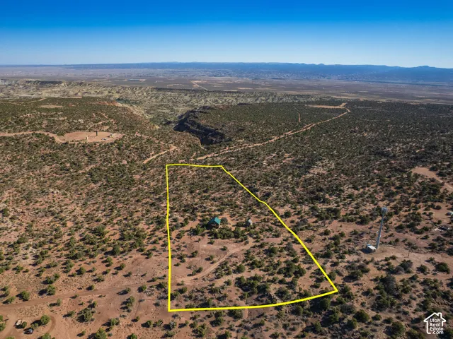 Expansive desert landscape featuring a marked property boundary, a single structure with a green roof, and rugged terrain
