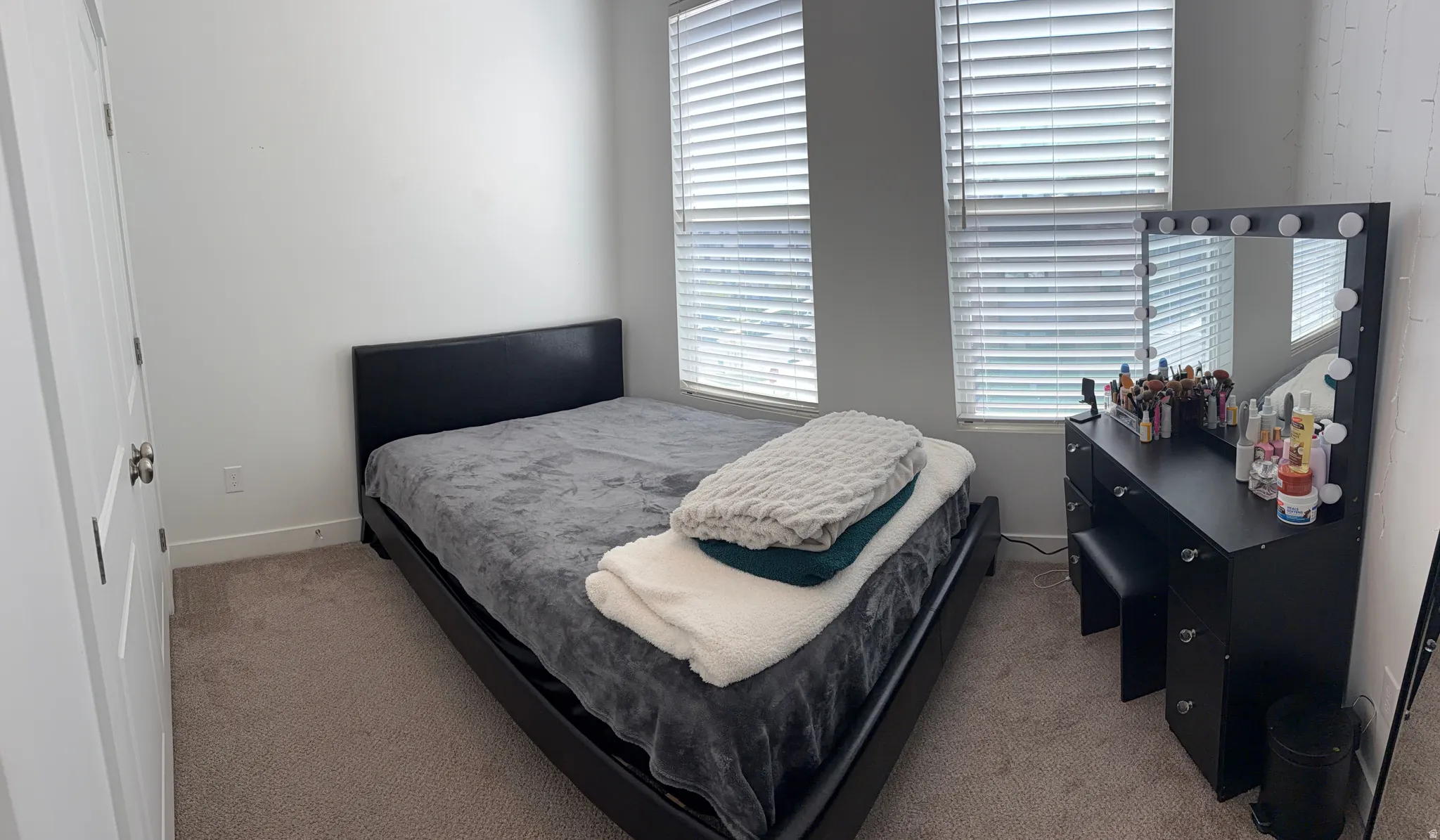 Bedroom featuring two windows with horizontal blinds, light gray walls, and carpet flooring
