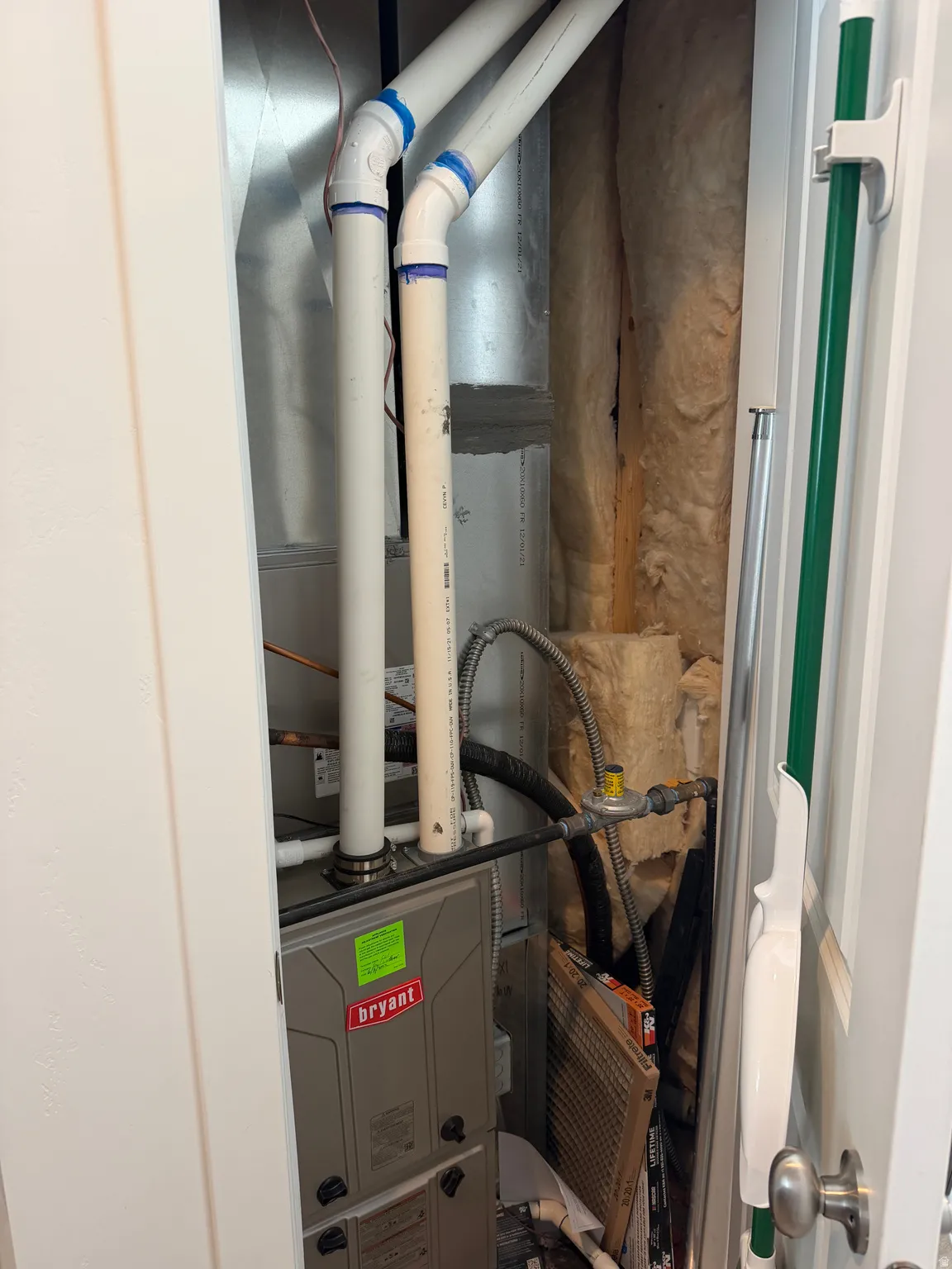 Utility closet featuring a Bryant furnace unit, PVC piping, and wall insulation