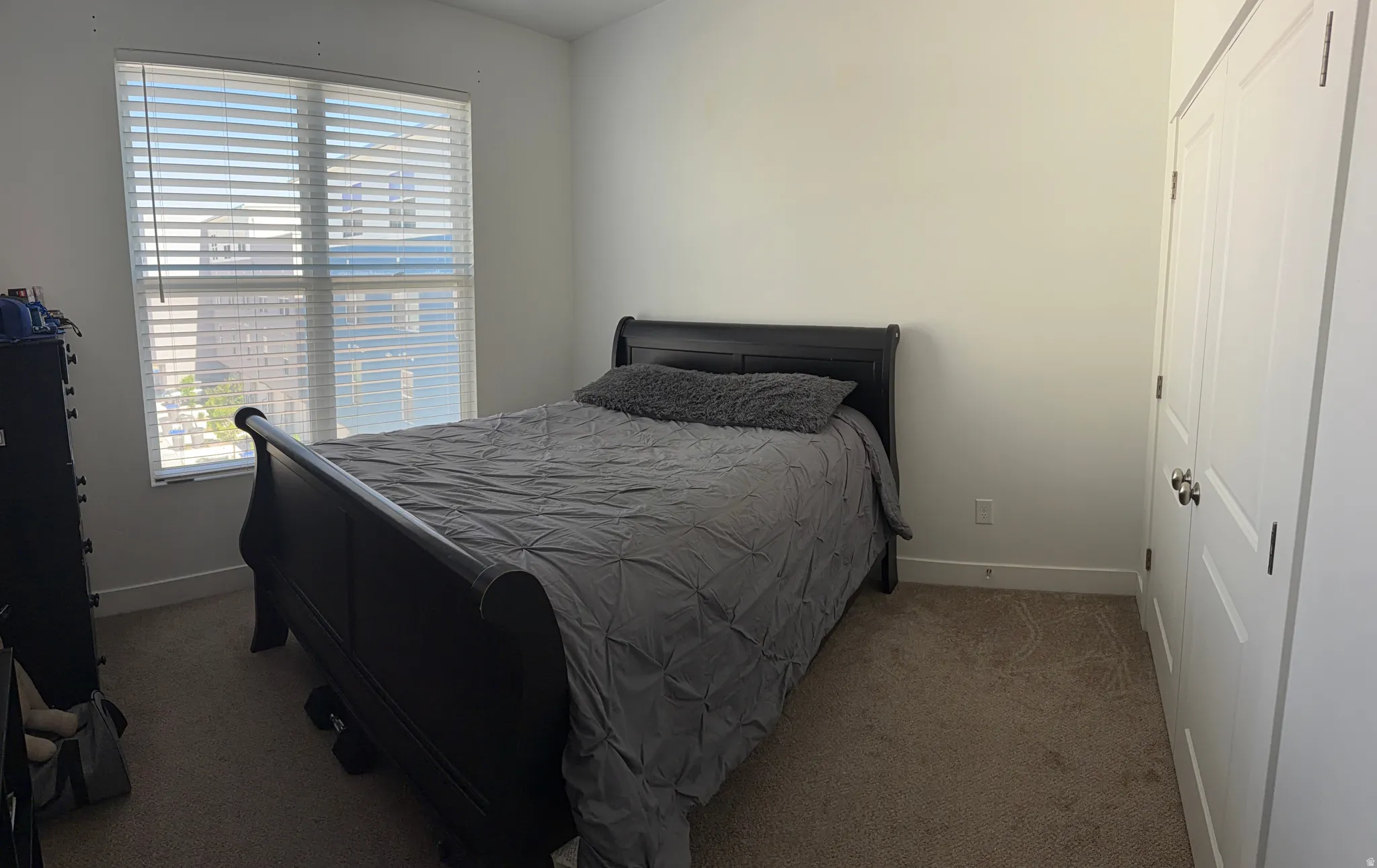 Bedroom featuring neutral wall paint, carpet flooring, a window with horizontal blinds, and a bi-fold closet door with brushed nickel hardware