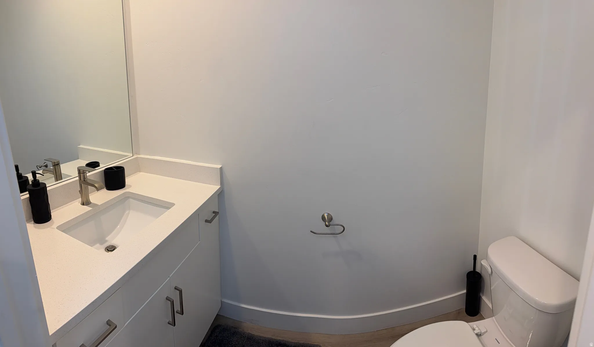 Bathroom featuring a white vanity with an integrated sink, brushed nickel faucet, and a large wall-mounted mirror