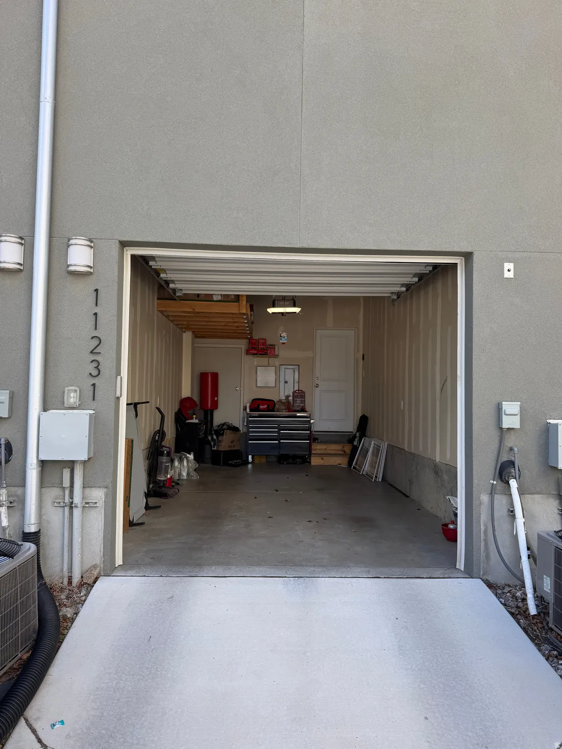 Attached garage with concrete flooring, overhead storage, and an interior access door