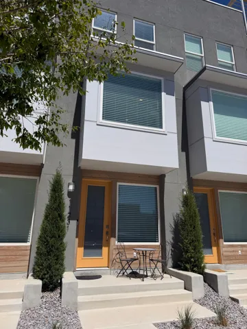 Contemporary townhouse exterior featuring a gray stucco facade and light wood-finish siding accents