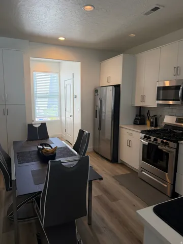 Modern kitchen featuring white cabinetry, stainless steel appliances, light countertops, and a white subway tile backsplash