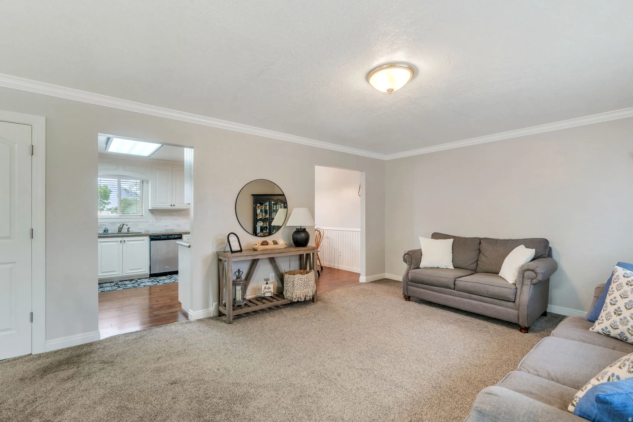 Carpeted living area featuring white crown molding and a semi-flush mount ceiling light