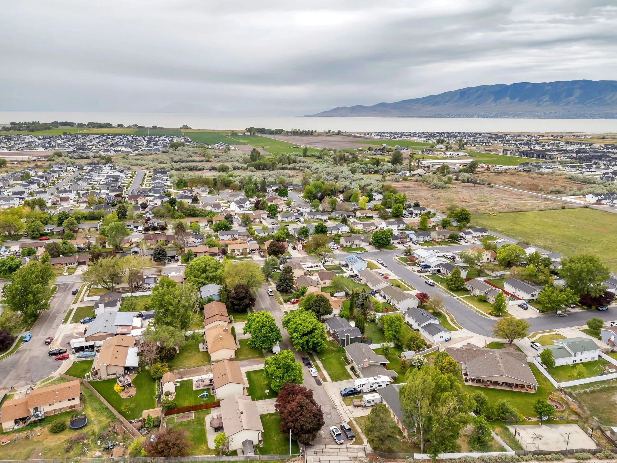 Aerial perspective of a residential neighborhood with a distant body of water and mountain range